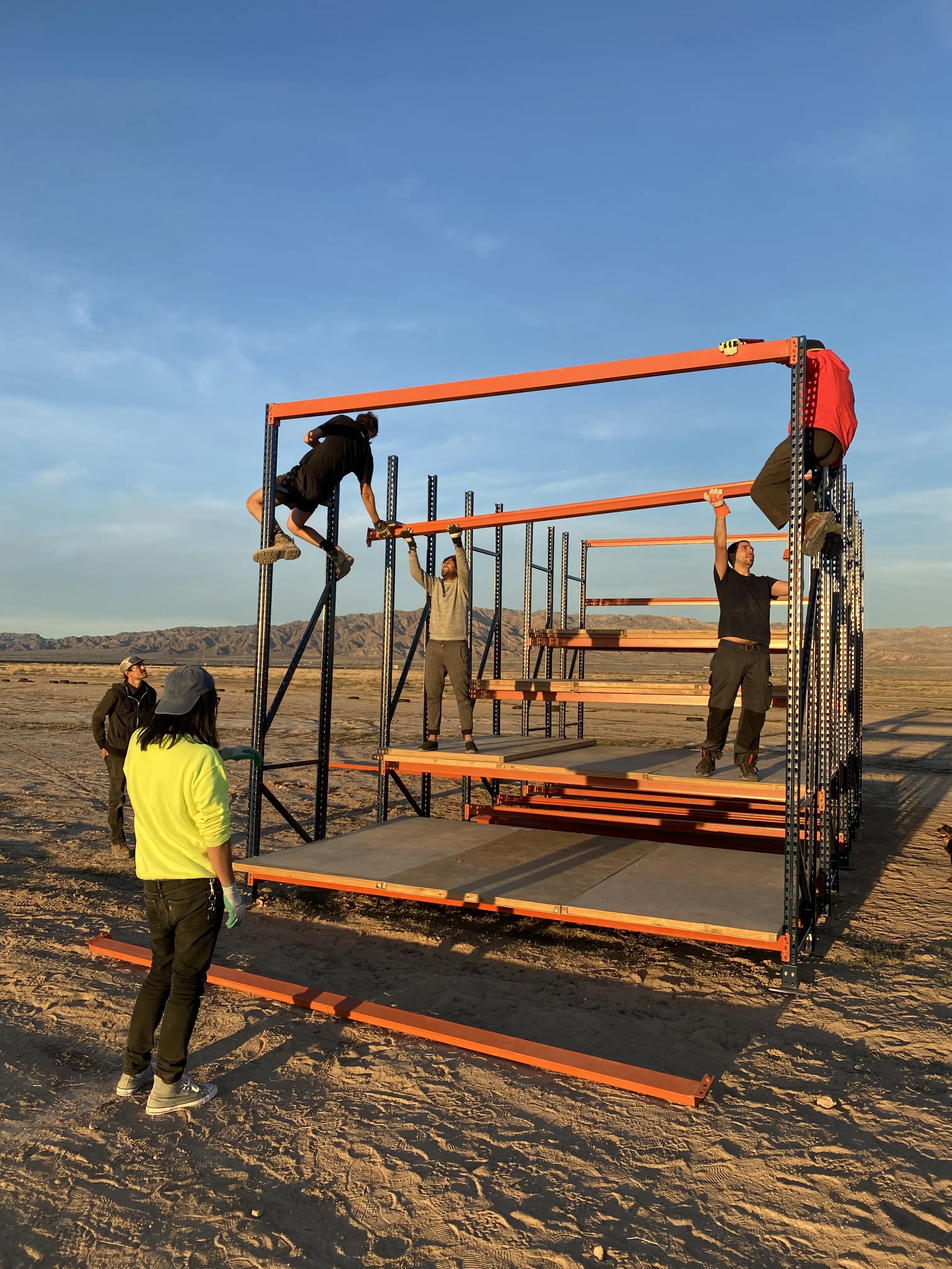 The crew assembling a pallet-rack structure at golden hour