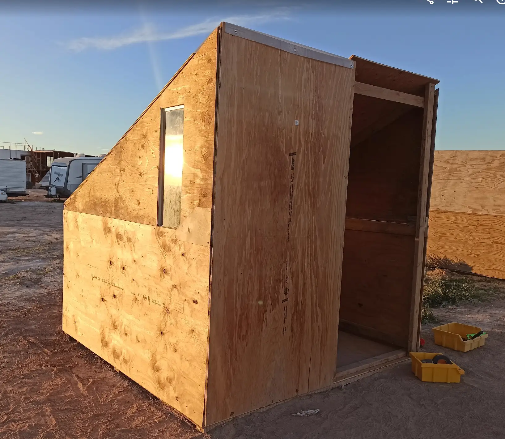A camp pod built from plywood at sunset