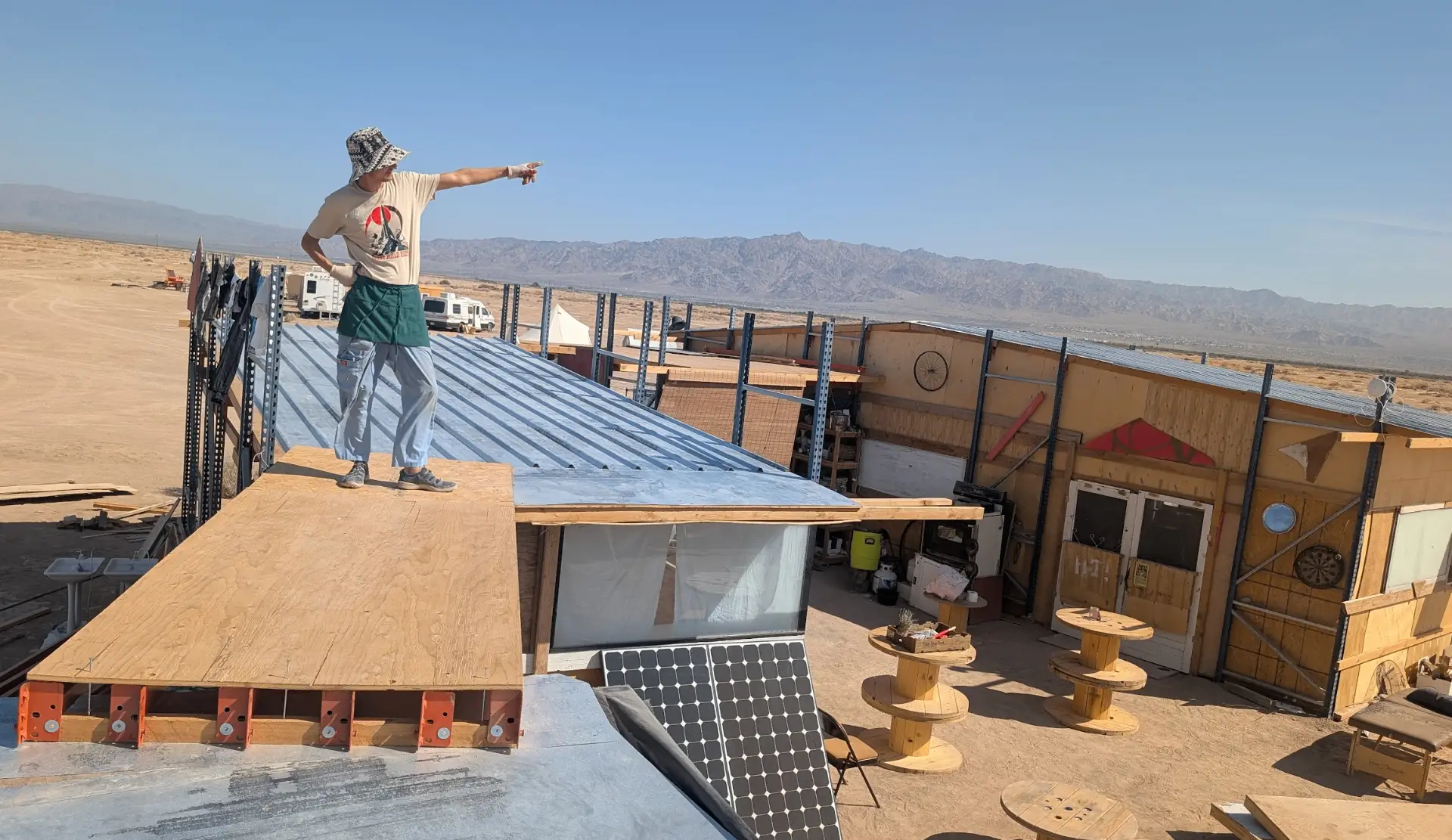 Standing on a rooftop pointing across the camp