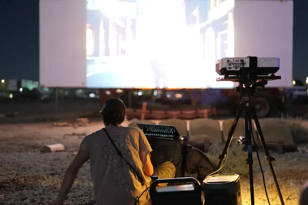 Projector and sound desk set up in front of the drive-in screen at dusk · 2024