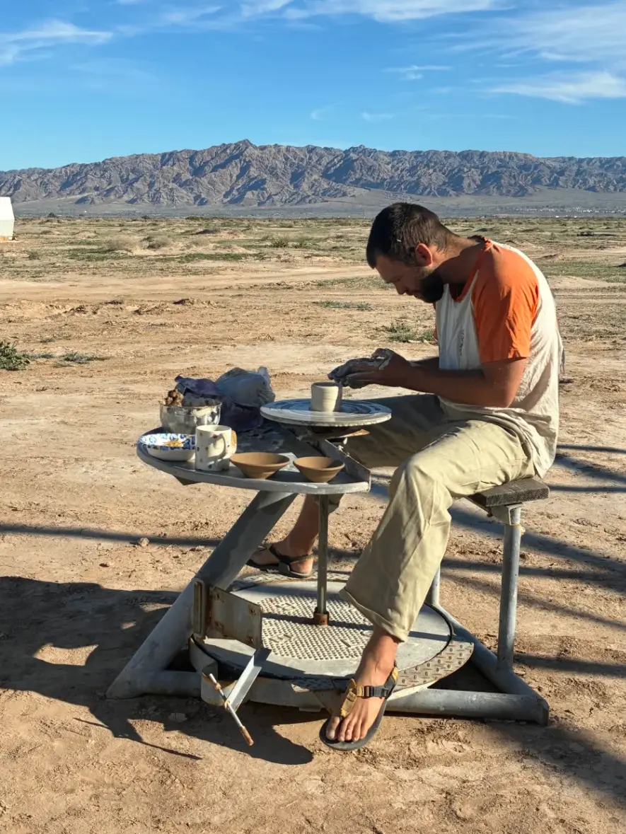 Throwing pottery on a wheel with mountains behind