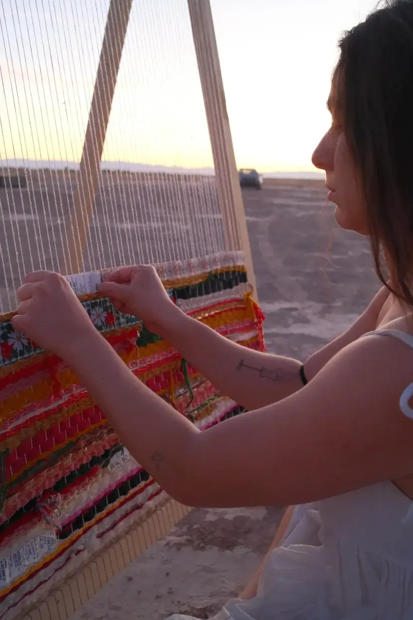 Weaving on a large loom at sunset in the desert