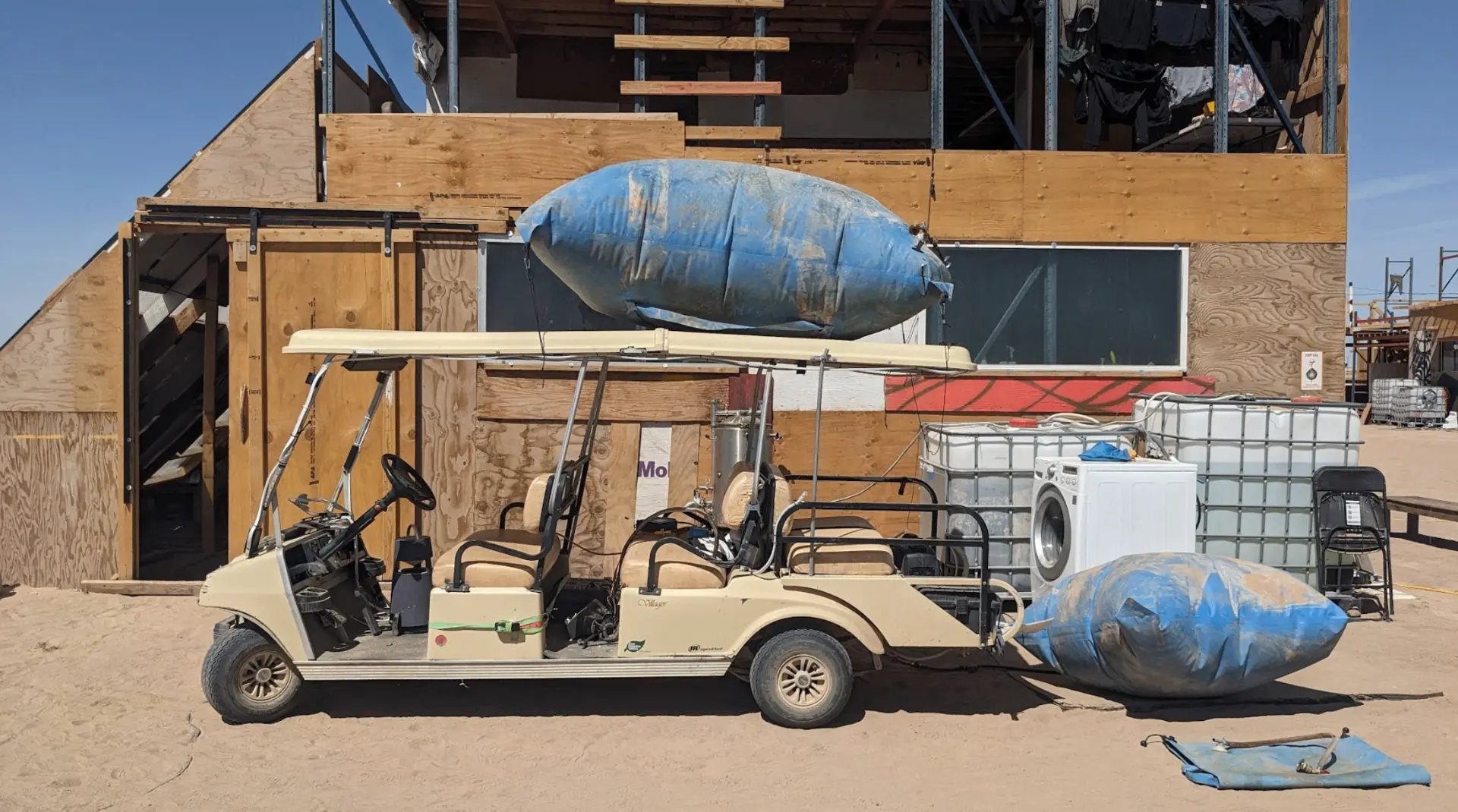 A modified golf cart parked at the workshop, loaded with water totes and bladders