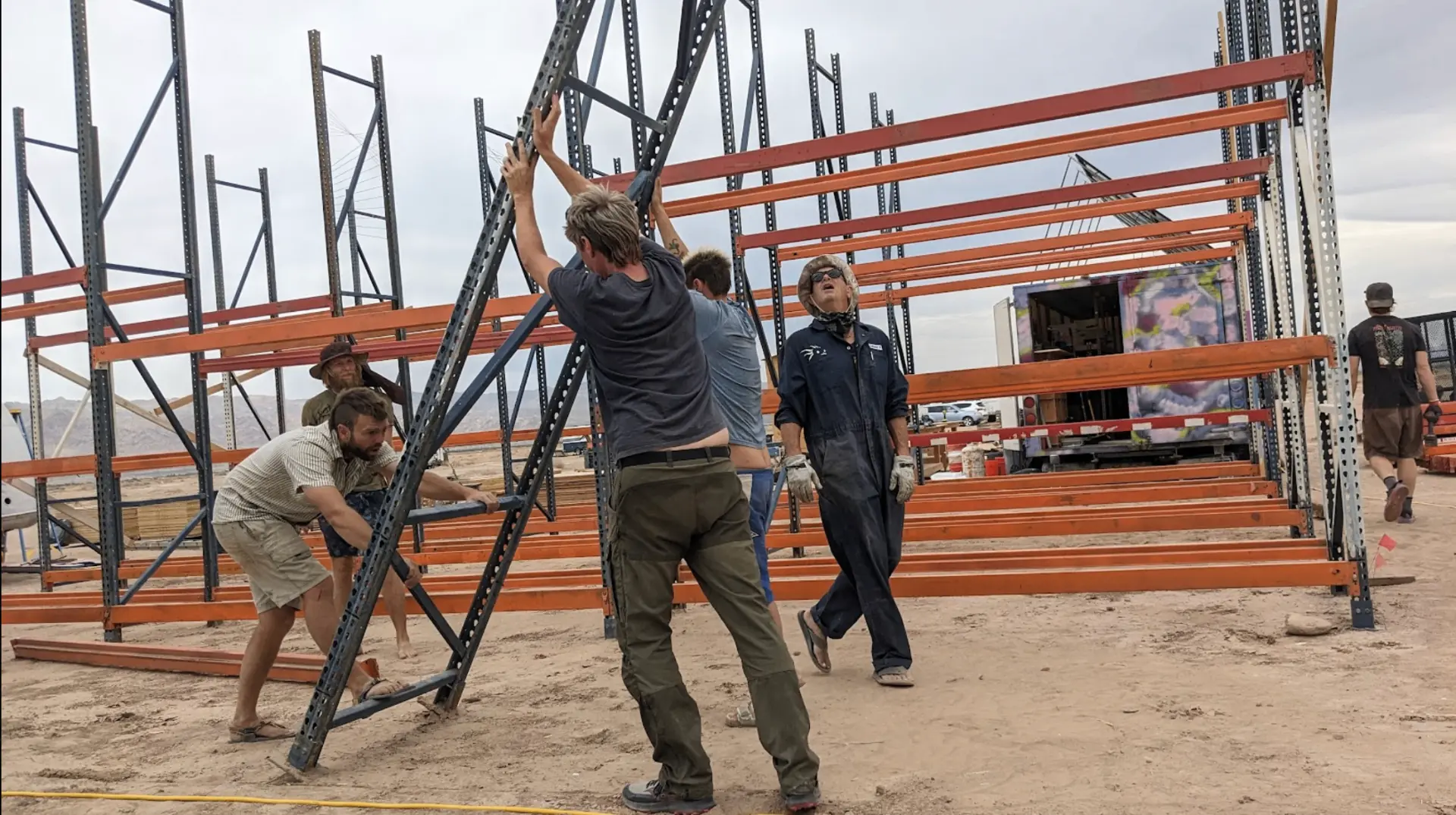 Residents raising the pallet-rack framing that becomes the desert workshop